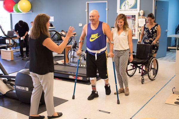 Therapist, Christy, assisting a patient to walk.