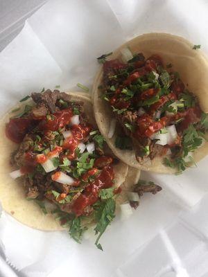 Steak tacos with fire red sauce, onion and cilantro