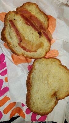 Croissant with one strip of bacon cut in half.