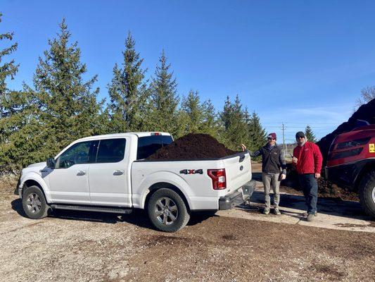 Happy customer with premium brown mulch loaded in the back of his pick up truck with our employee of the year.