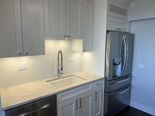 Anther view of kitchen sink and cabinets above fridge