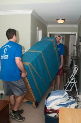 RSM crew moving a dresser wrapped up in a heavy duty furniture pad.