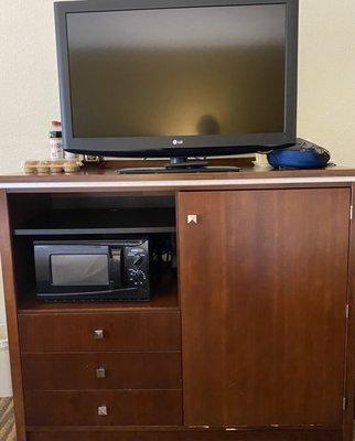 Cabinet with small microwave, mini-fridge, and TV.