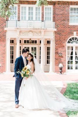 A bride and groom taking portraits in front of the mansion.