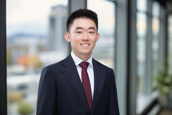 A young Asian man in a suit and red tie smiles for his personal branding headshot, taken at our Cincinnati photography studio.