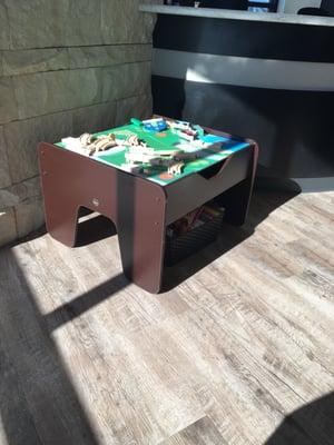 Kids train table with a basket of books underneath in the waiting area