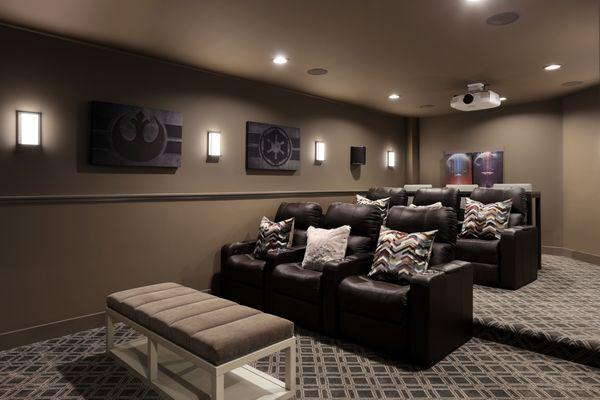 The custom home theater feels cozy yet luxe with Tuftex patterned carpet, leather seating and paint in Sherwin Williams 7026 Griffin.