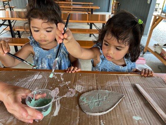 Two small children painting a clay leaf at a brewery.