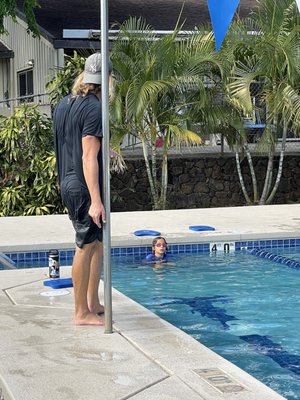 Instructor teaching our kid swimming.