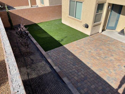 Paver patio with artificial turf. Retaining wall flower bed