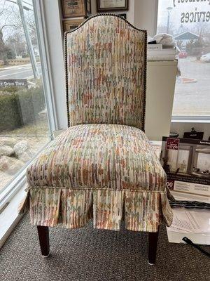 Reupholstered dining room chair with nails finished with self welt and a pleated skirt.