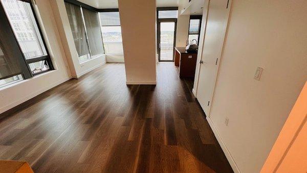 The image showcases a beautifully installed dark wood-toned engineered hardwood flooring in an apartment complex.