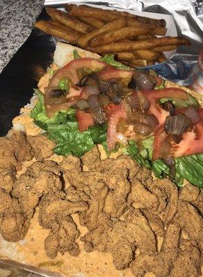 Fried shrimp poboy. Poboys are dressed with crisp romaine lettuce, juicy sliced tomato, grilled onions, swamp sauce and a pickle spear