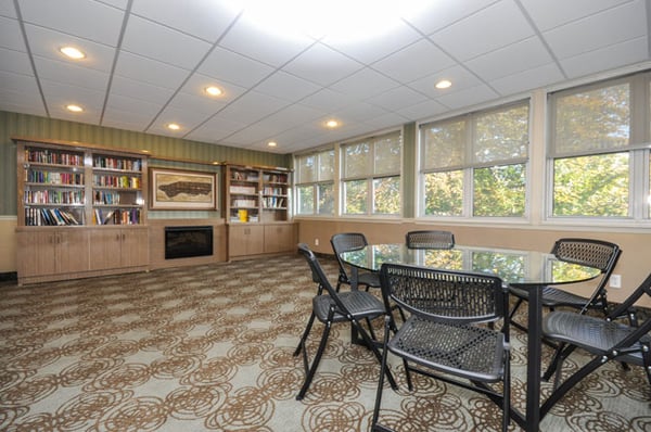 Facility library. Multiple stocked shelves of various genres and comfortable seating. Residents may freely borrow books.