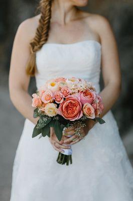 Stunning coral and peach hand tied bridal bouquet with garden roses, stock, ranunculas, spray roses, and seeded eucalyptus