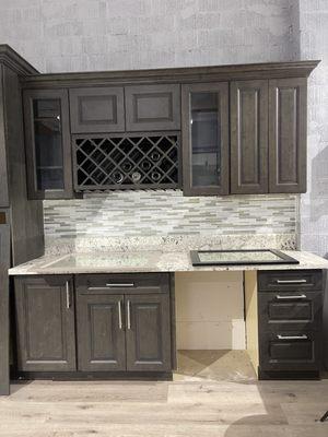 Ash brown shaker cabinets with glass door cabinets and silver handles. Also with a  wine rack.