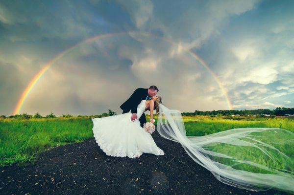 Wedding kiss in front of a rainbow