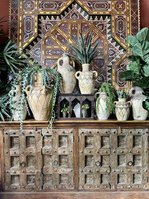 A buffet made from old Indian doors and a Moroccan handpainted ceiling panel with a collection of Berber pots.