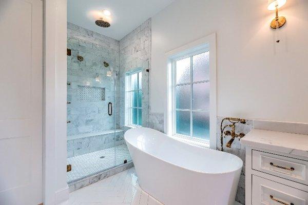 Marble shower with dual shower heads, seamless glass and free-standing bathroom tub