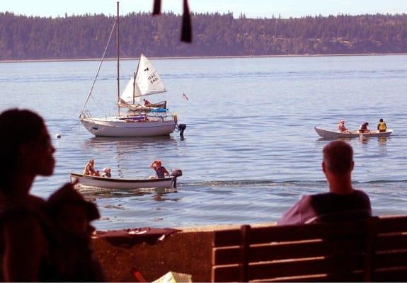 Visitors watch boats from the boathouse porch