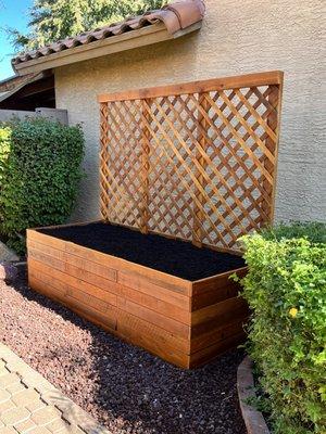 A redwood garden box with a lattice for vining plants.