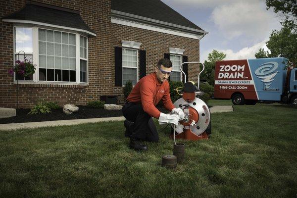 Technician unclogging a main line with a cable machine from a yard cleanout. Sewer, Drains, Main, Lateral, Clean-Out, Snake