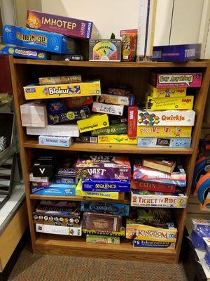 Shelf overflowing with board games people can demo