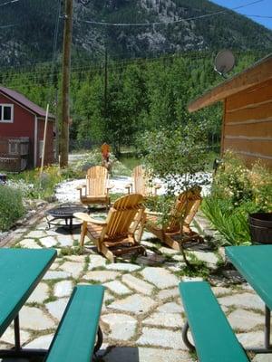 Stone patio with a small fire pit & grill.