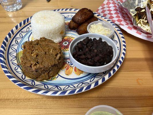 The plate with rice, black beans, shredded beef, plantains, and cheese.