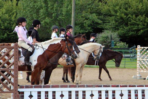 A group of riders performing at a hunter jumper competition.