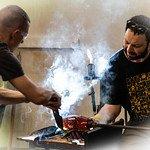 Instructor Brian Frus assists fellow instructor Carmi Katsir at the work bench during a glassblowing dmeonstration