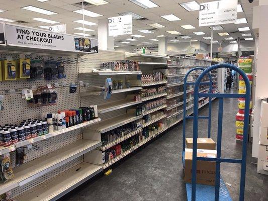 Bare shelves along with hand trucks and boxes blocking the aisle.