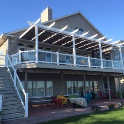 White vinyl pergola with retractable shades installed over decking.