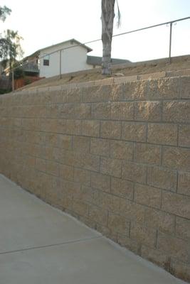 New split face retaining wall plus new standard grey patio down below.