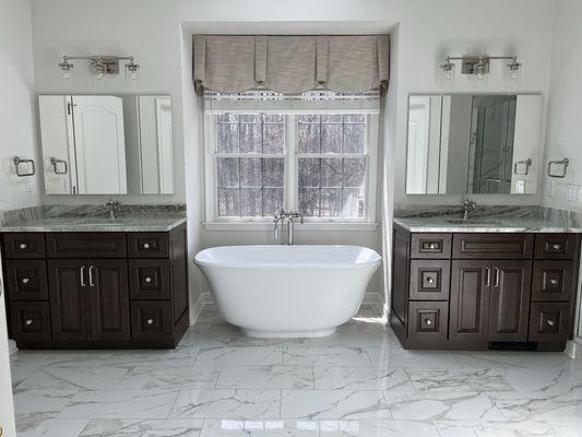 Custom bathroom with jack and Jill sinks, large format marble floor tile, freestanding tub and freestanding faucet in Novi, Michigan