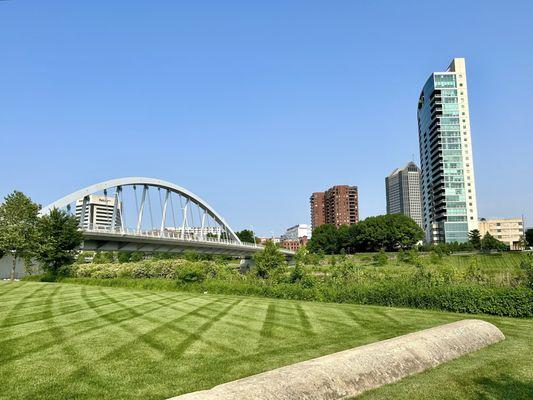 Walking through the park with Columbus' Main Street Bridge and high rise buildings in the background.