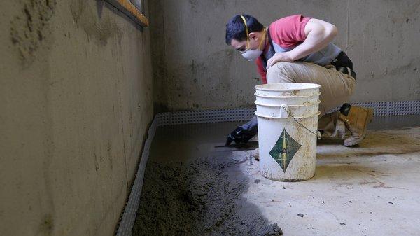 Troweling Supercrete into sections of missing concrete floor.