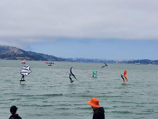 Wind surfers on foilboards performing on the water