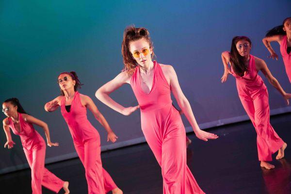 High school girls in pink costumes perform in dance video at summer camp