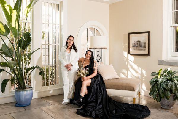 posing together on a chaise in the atrium before the wedding