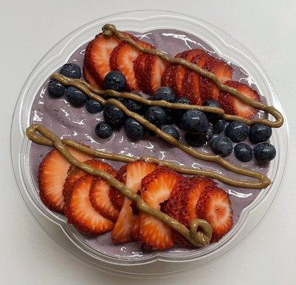 Protein acai bowl topped with fresh blueberries, strawberries and almond butter.