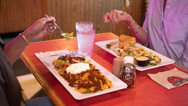 Two friends enjoying a Deluxe Taco Salad (left) and a Cobb Salad.