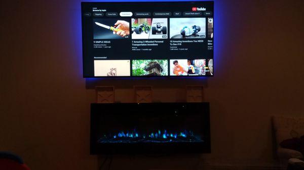 65" tv with led lights behind the tv and electric fireplace mounted