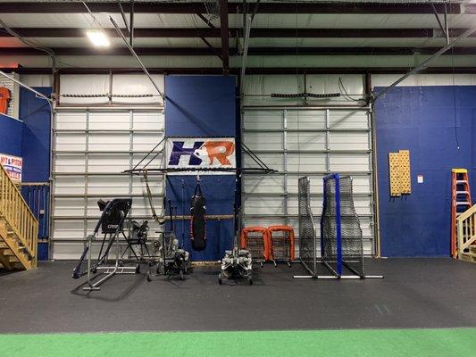 Machines, and other equipment are stored in the area off the side of the playing surface/batting cages.