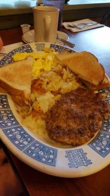 Sausage patty and white  buttered toast with sliced potatoes.