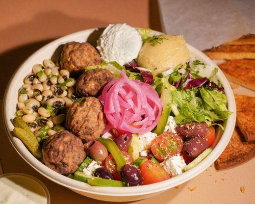 Greek meatballs, lightly fried bowl. Healthy beans, green salad, Greek salad, hummus, dips and feta. pickled onions.