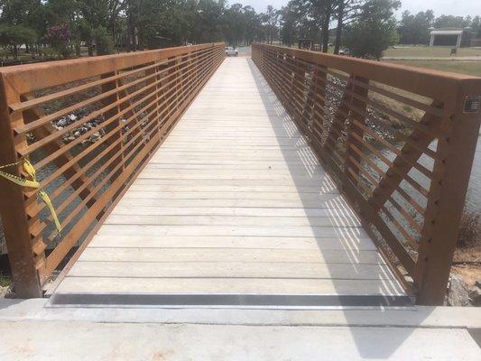 Pedestrian foot bridge with 2"x8" concrete wood grain texture to replace wood for prevention of rot.