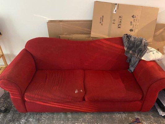 Old, sad red couch. Sagging in the middle and multiple rips in the fabric.