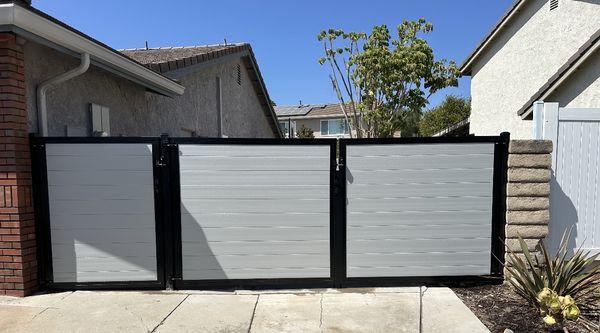 Grey horizontal vinyl privacy double gates with also a single gate with a black aluminum frame