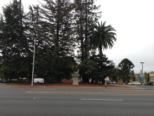 Wide shot of Junipero Serra redwood bust with S El Camino Real in foreground.